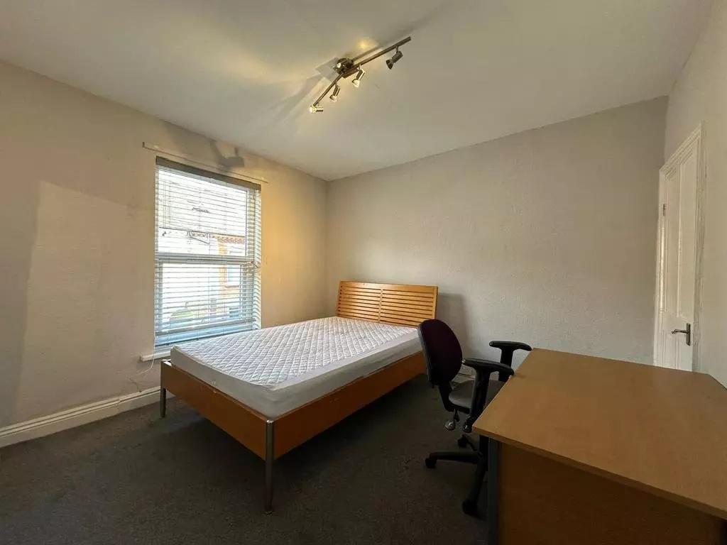 A neat double bedroom featuring a wooden bed fr...