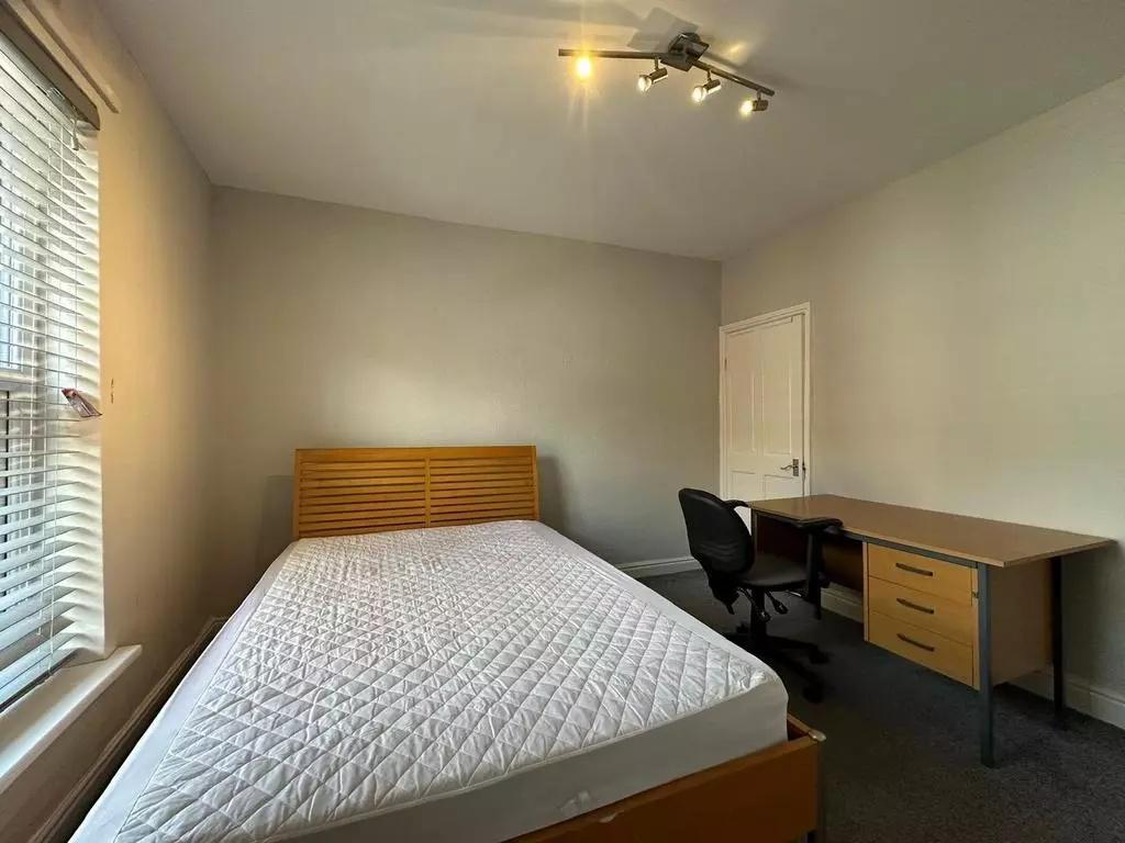 A tidy double bedroom featuring a wooden bed fr...