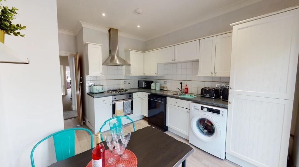 A modern kitchen featuring white cabinetry, bui...