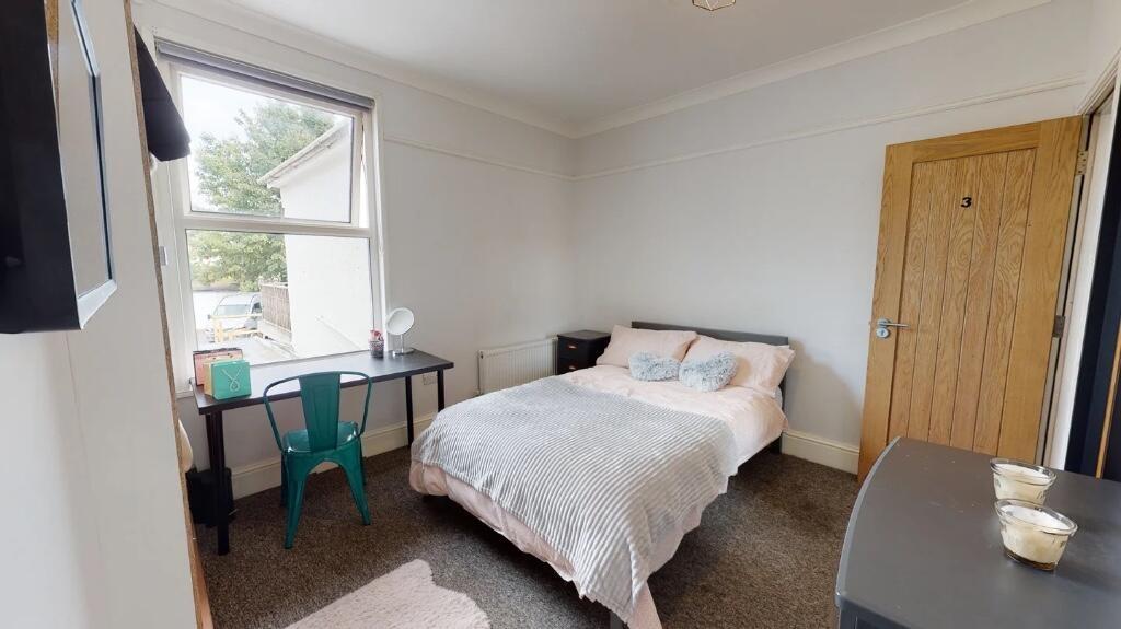 A cosy, well-lit double bedroom featuring a com...