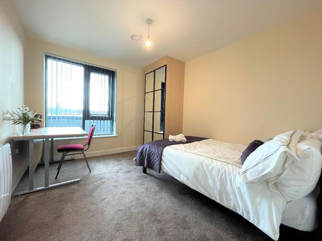 A bright and cozy single bedroom featuring a co...