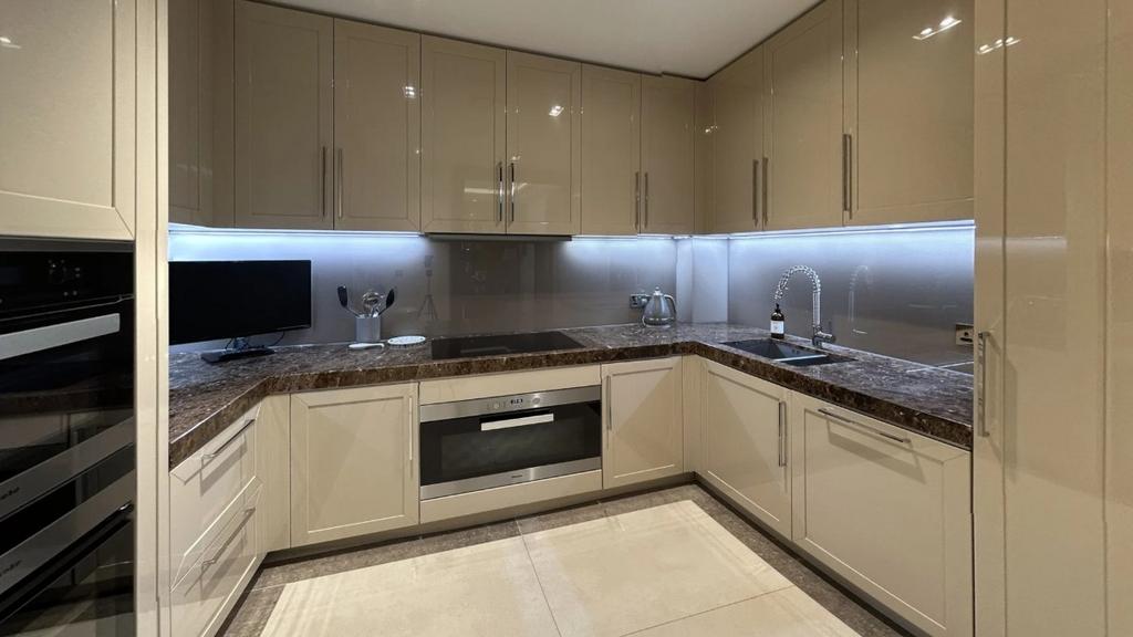 Modern kitchen featuring sleek beige cabinetry,...