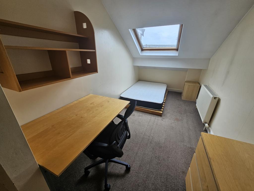 A compact, tidy single bedroom featuring a skyl...