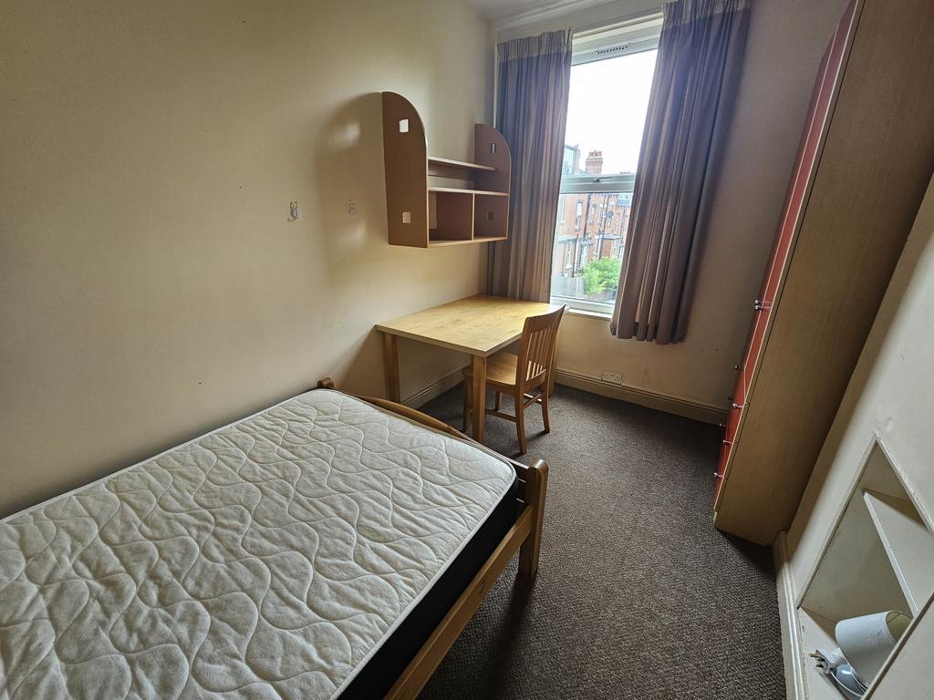 A cozy single bedroom featuring a comfortable b...