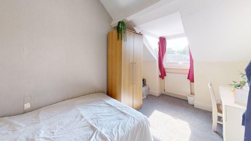 A bright and cozy single bedroom featuring a co...