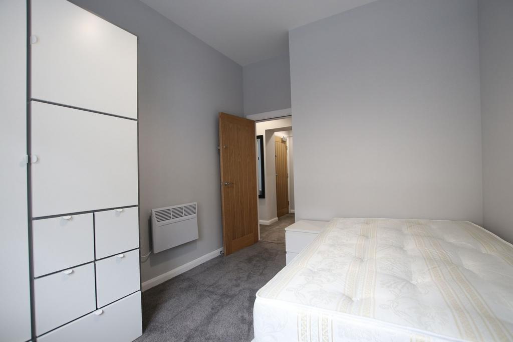 A neat and tidy single bedroom featuring soft g...