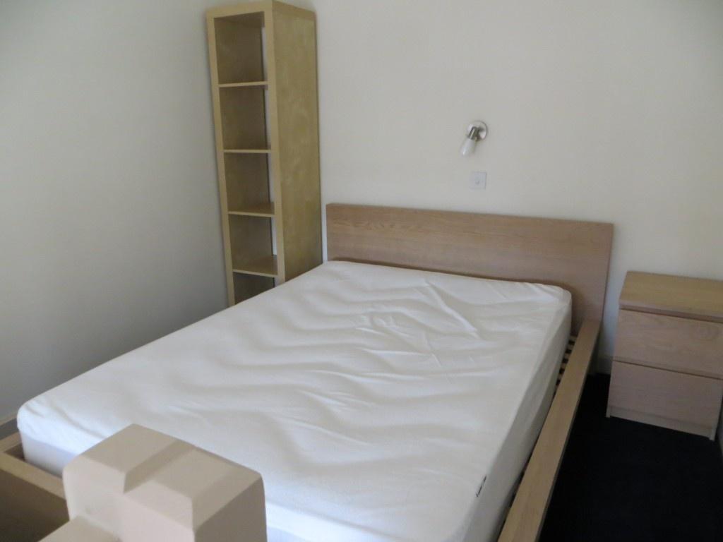 A neat double bedroom featuring a wooden bed fr...