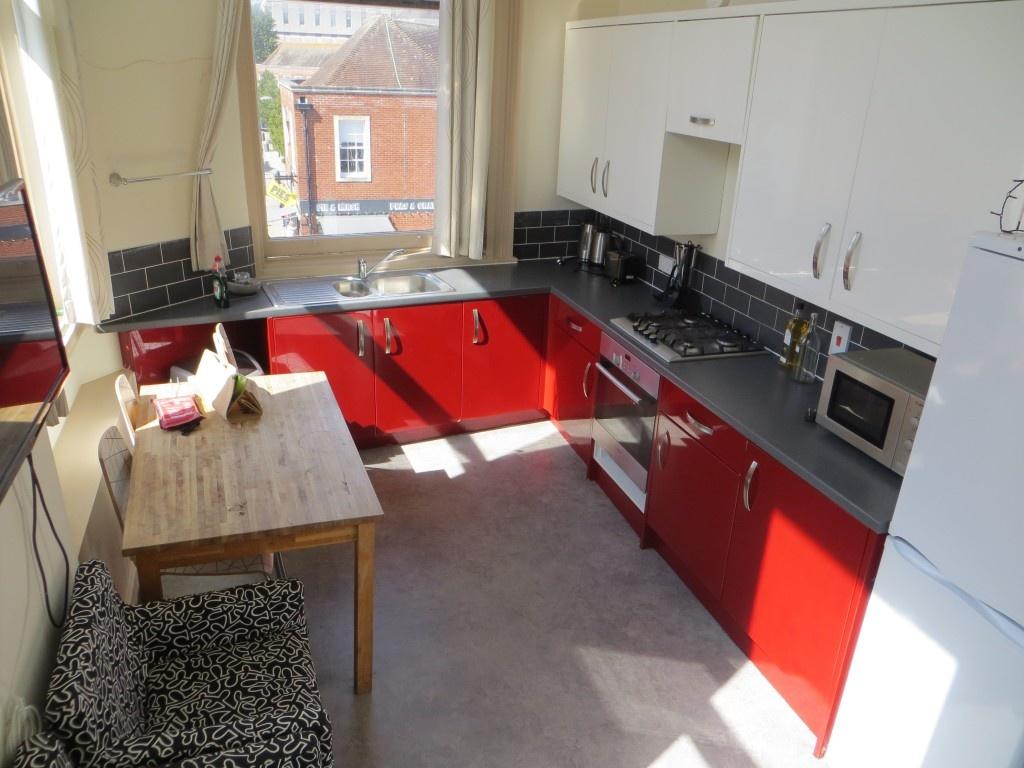Bright and modern kitchen featuring vibrant red...
