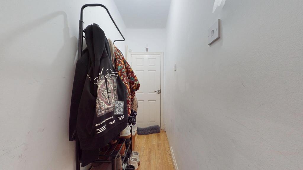 A narrow hallway with wooden flooring and white...