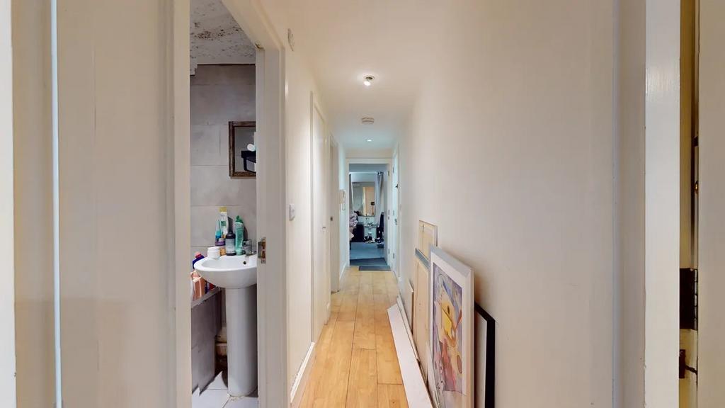 A bright hallway with wood flooring and white w...