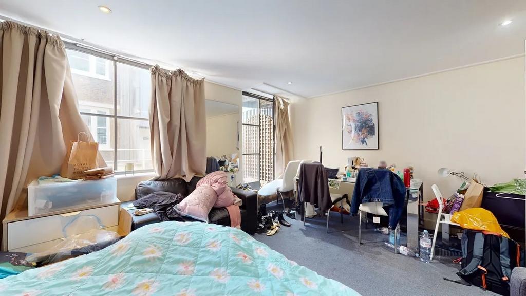 Bright double bedroom featuring a cozy bed with...