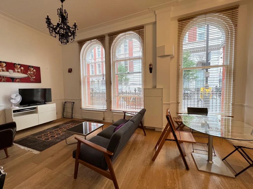 A stylish living room featuring large arched wi...