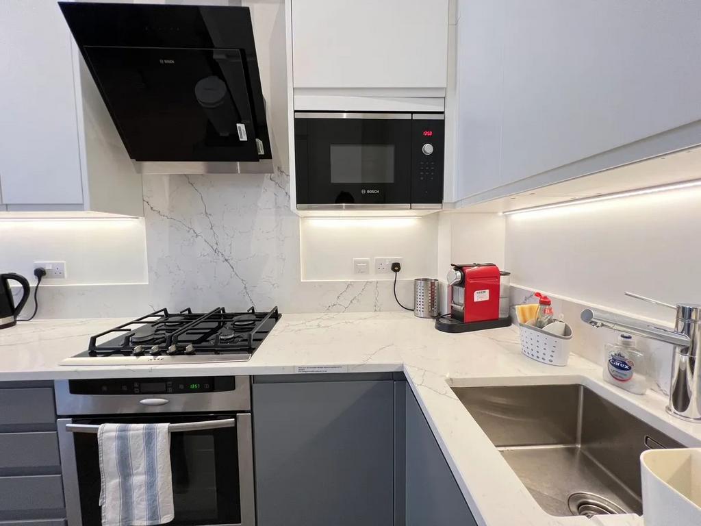 A modern, sleek kitchen featuring a marble-effe...