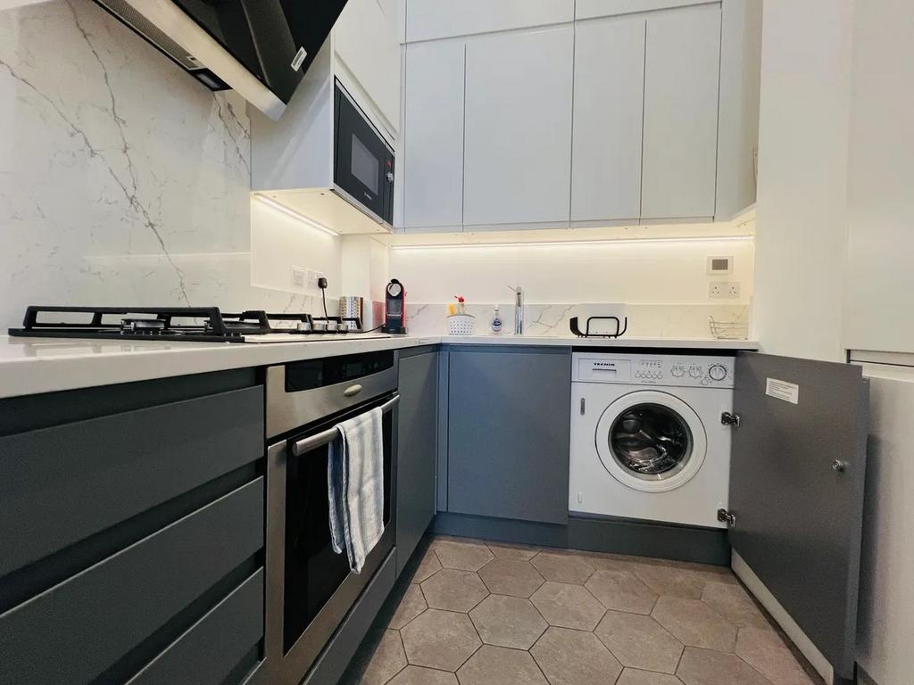 A modern, compact kitchen featuring sleek grey ...