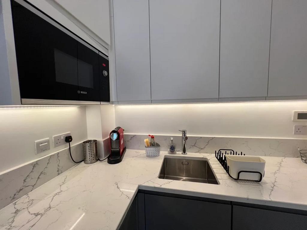 A modern kitchen area featuring sleek white cab...
