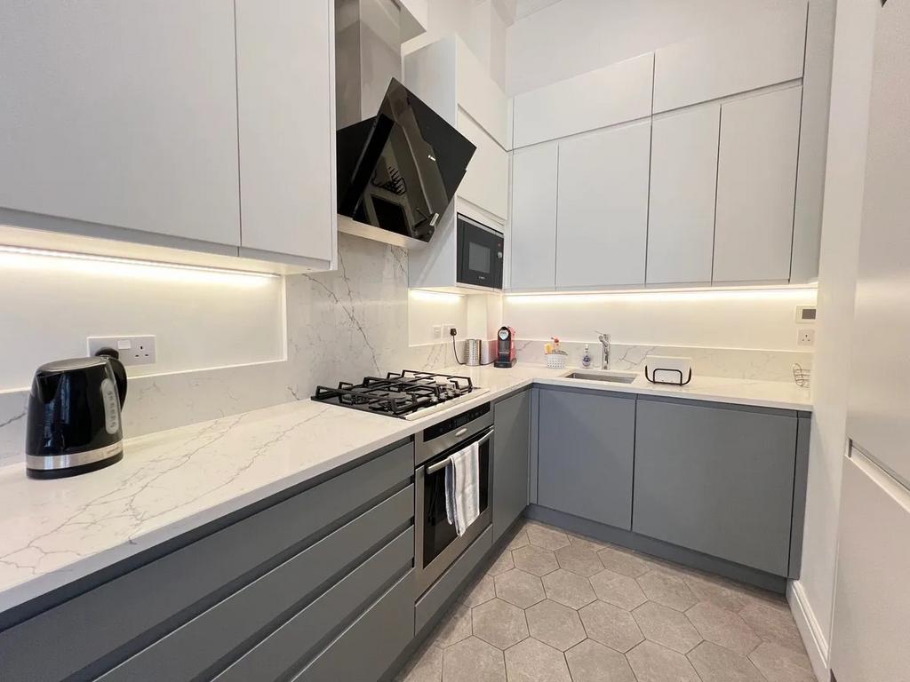 A modern kitchen with sleek grey and white cabi...