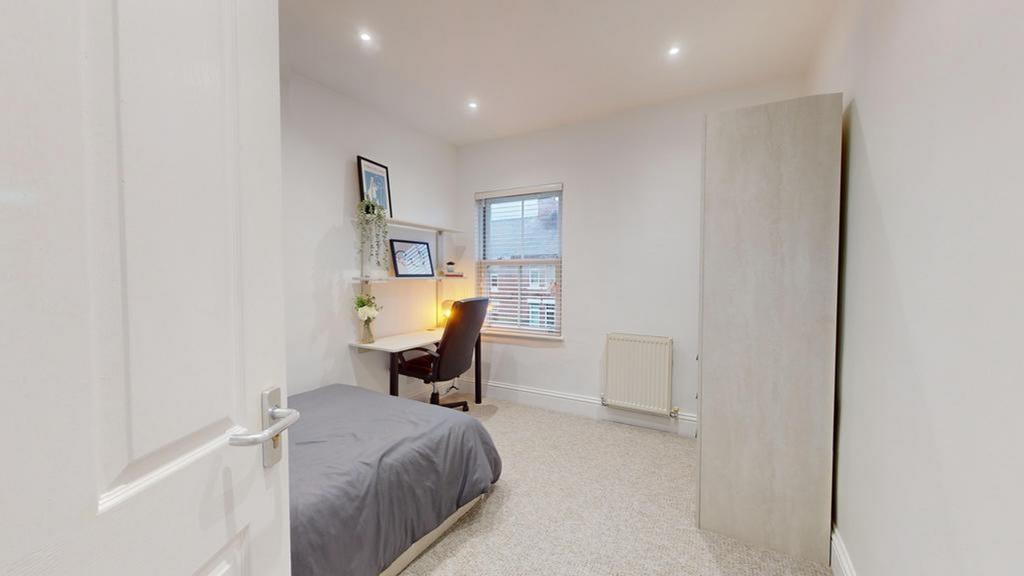 A bright and inviting double bedroom with a des...