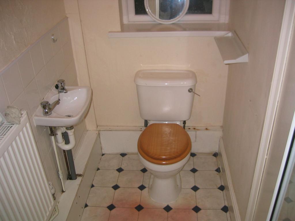 Compact restroom featuring a white toilet with ...