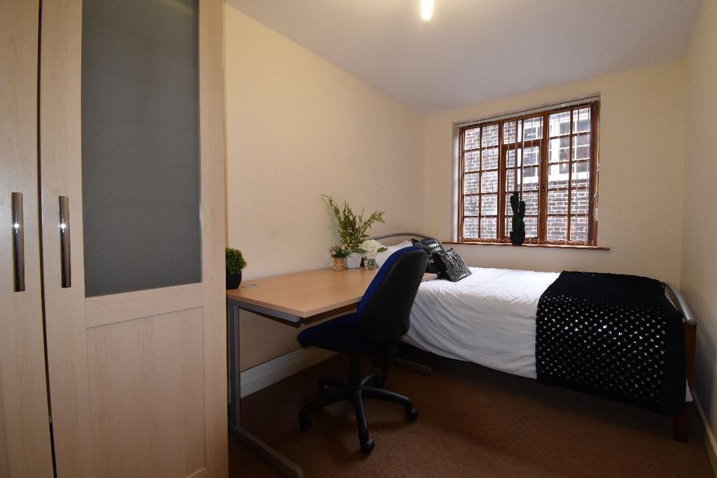 A cozy single bedroom featuring a neatly made b...