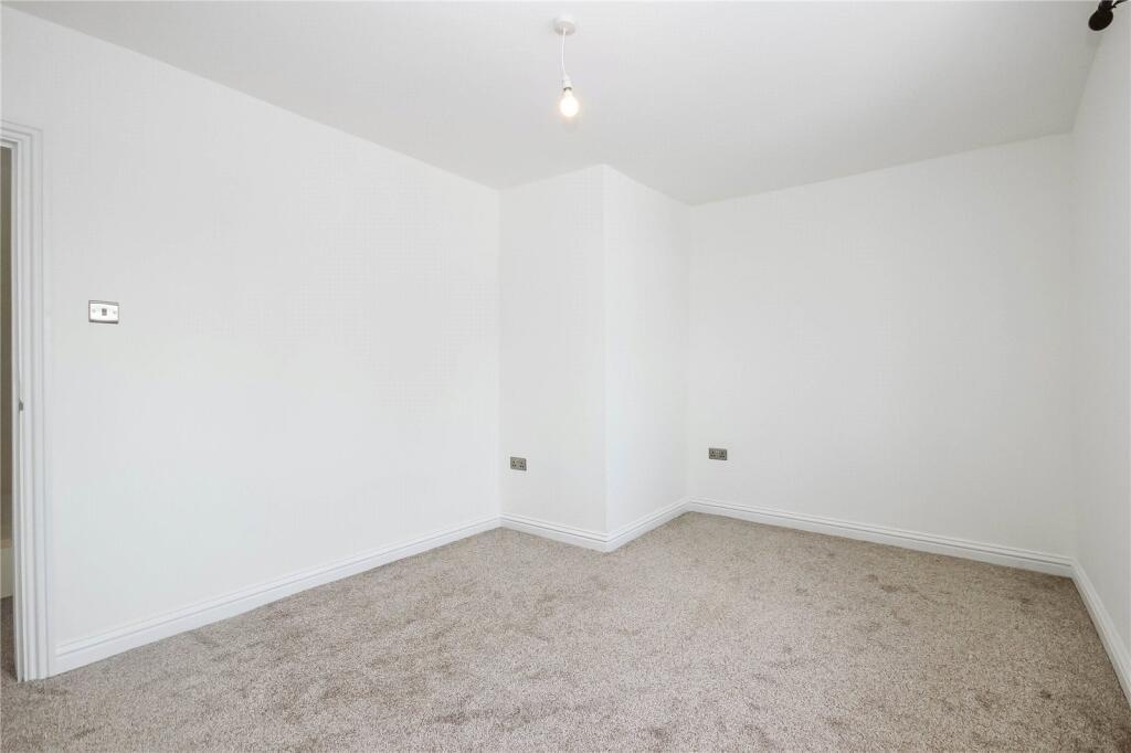 Bright, empty bedroom with neutral walls and ca...