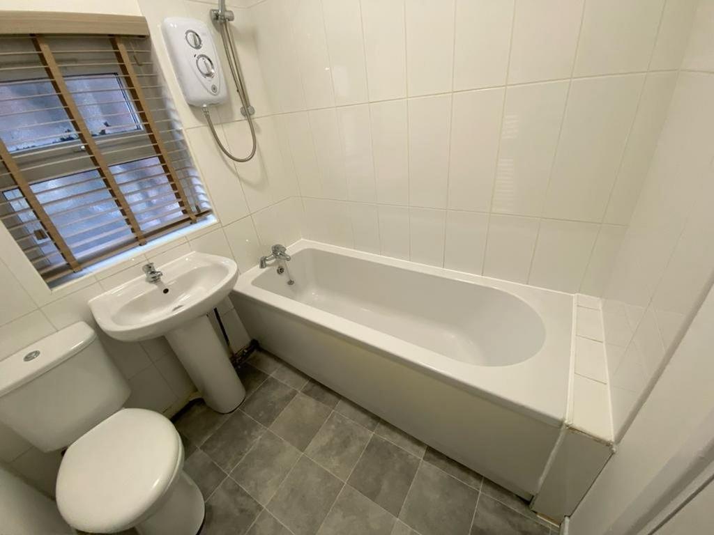 A bright and clean bathroom featuring a bath, s...