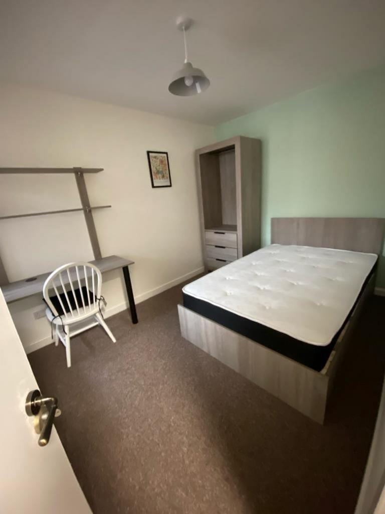 A spacious and tidy double bedroom with a desk,...