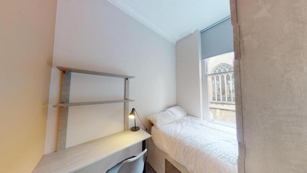 A bright and tidy single bedroom featuring a de...