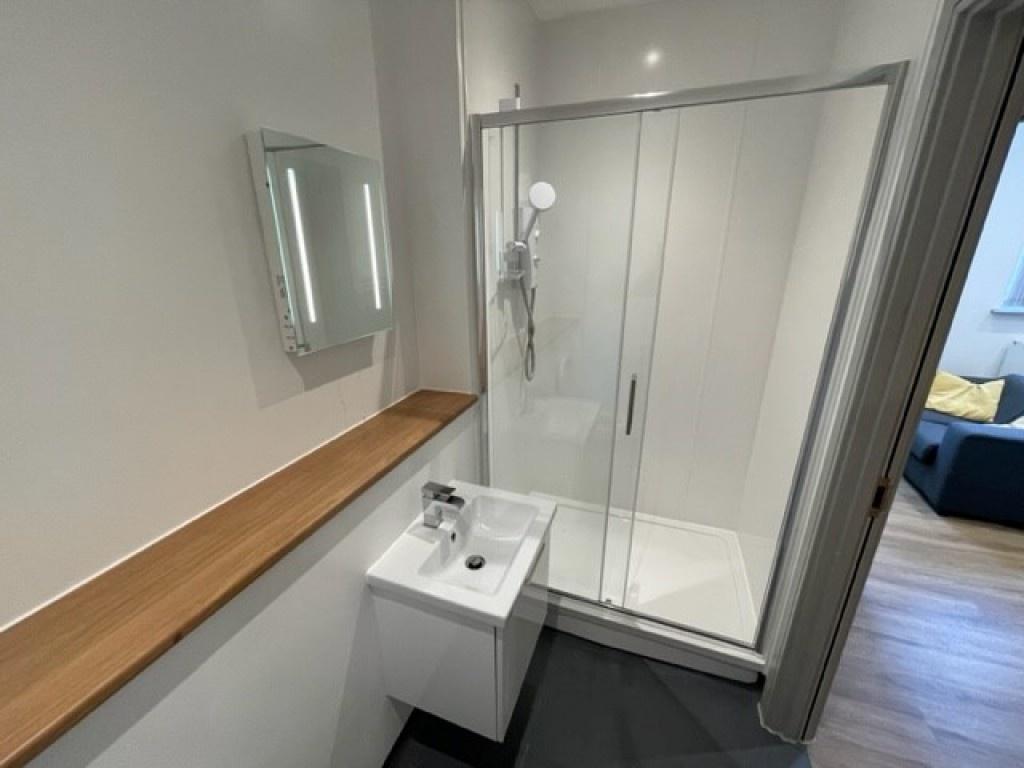 A modern bathroom featuring a clear glass slidi...
