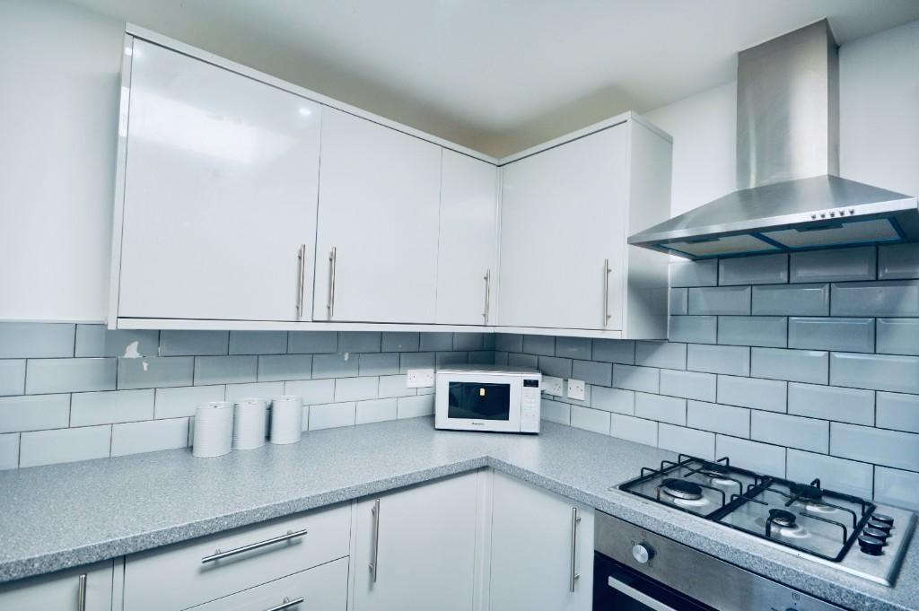 Modern kitchen featuring sleek white cabinetry,...