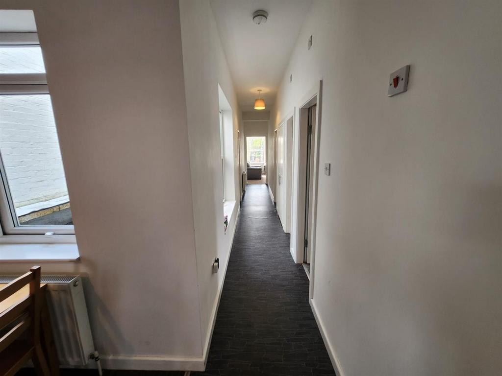 Long, bright internal hallway with neutral wall...