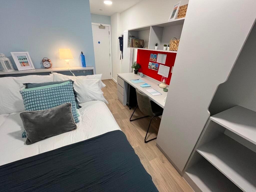 A modern, well-organized single bedroom featuri...