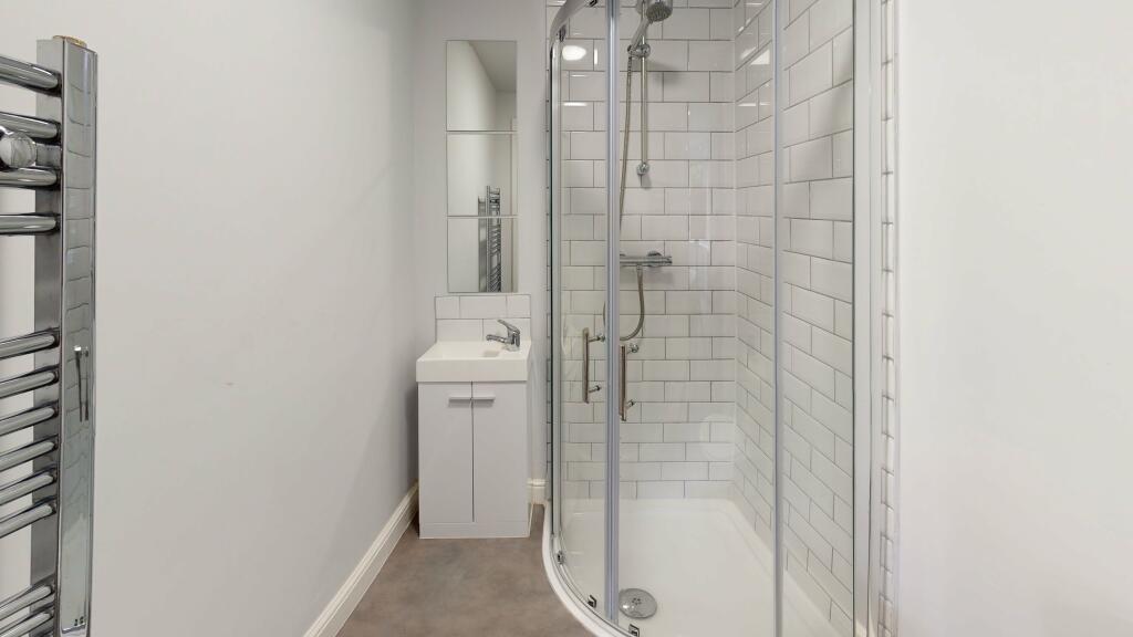 Modern bathroom featuring a sleek curved glass ...