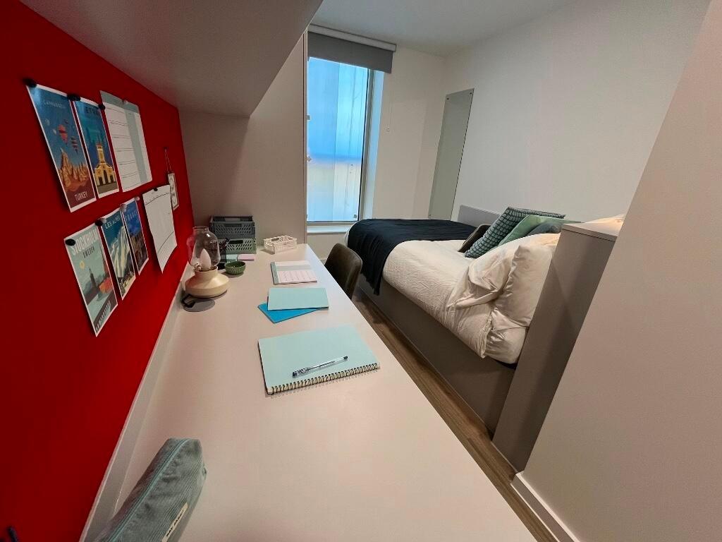 A neat and well-organized single bedroom featur...