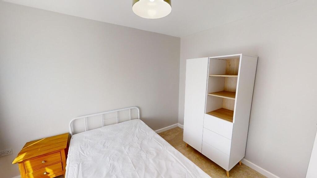 A neat and simple bedroom featuring a white bed...