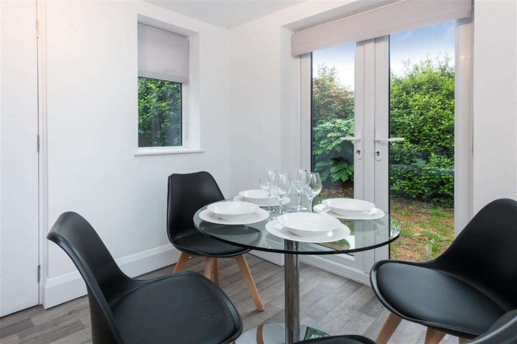 A modern dining area with a round glass table s...
