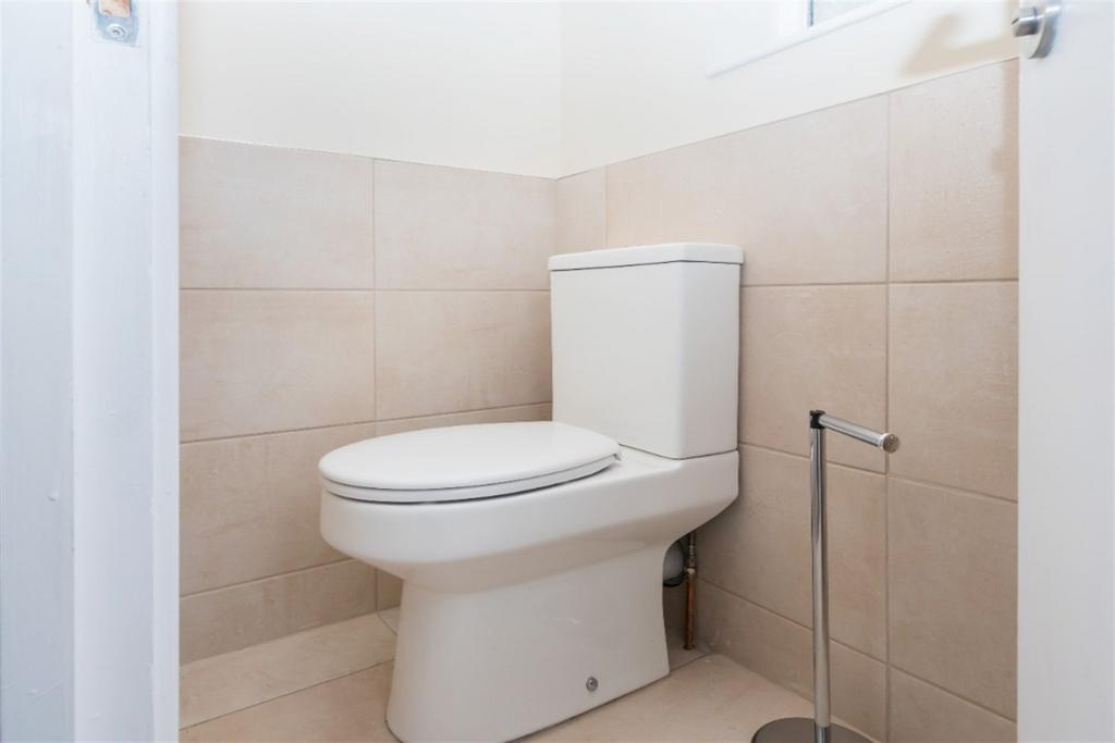 Bright and clean compact toilet area with neutr...
