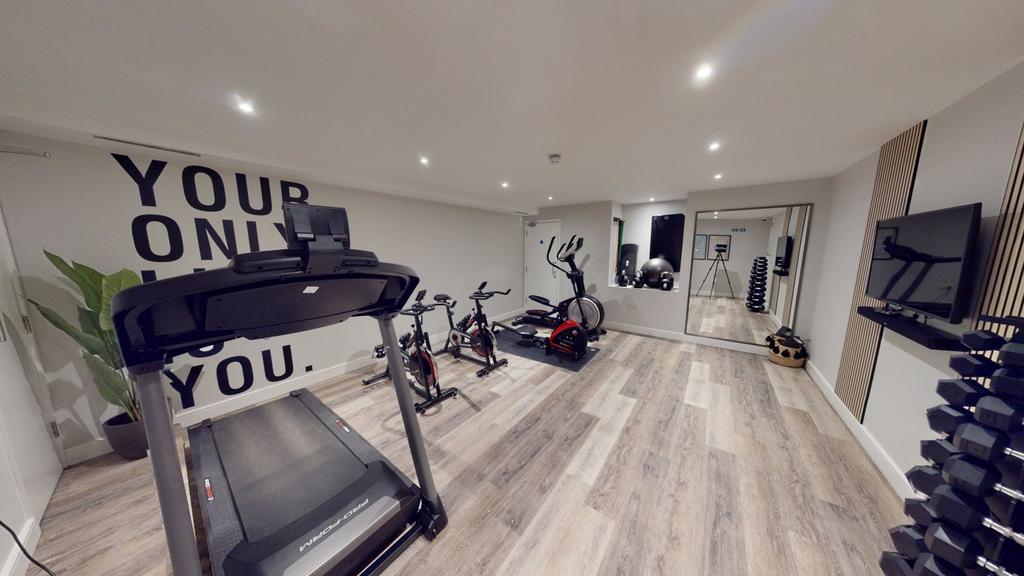 A spacious and well-lit gym equipped with moder...