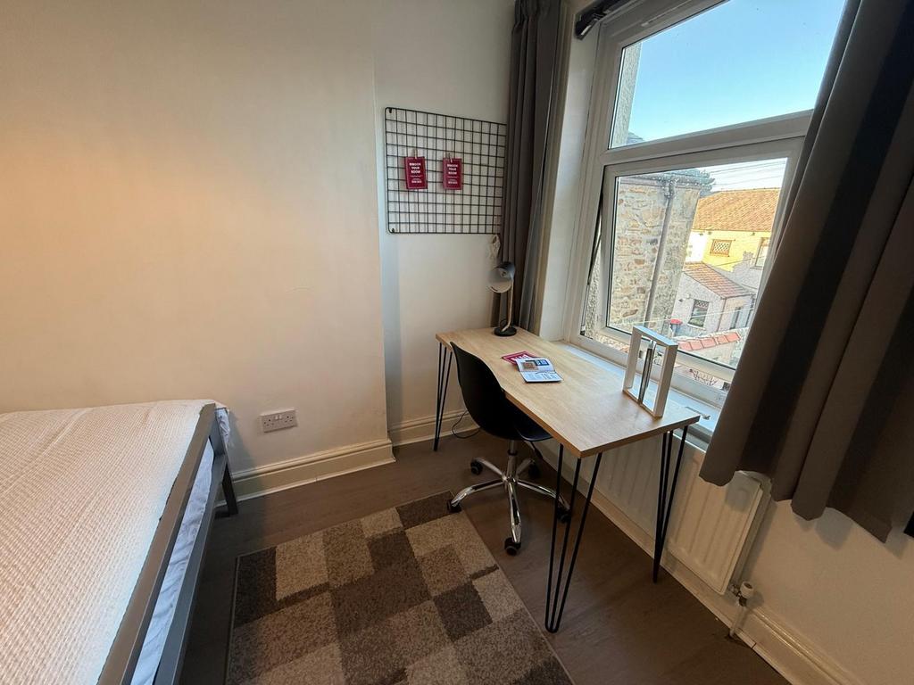 Bright single bedroom with a window-side desk, ...