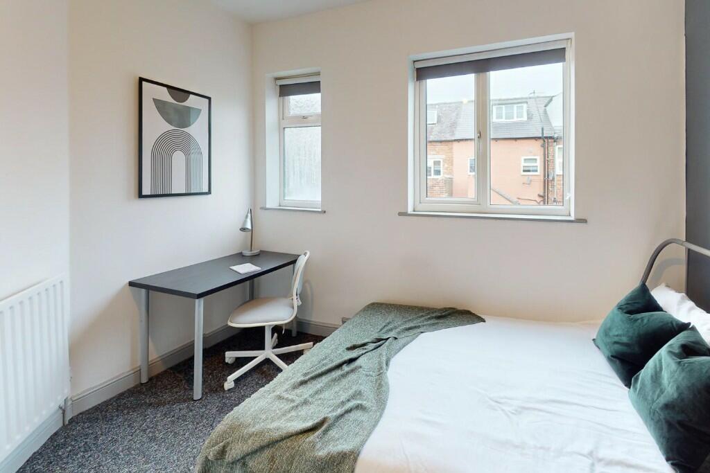 A bright single bedroom featuring a cozy bed dr...