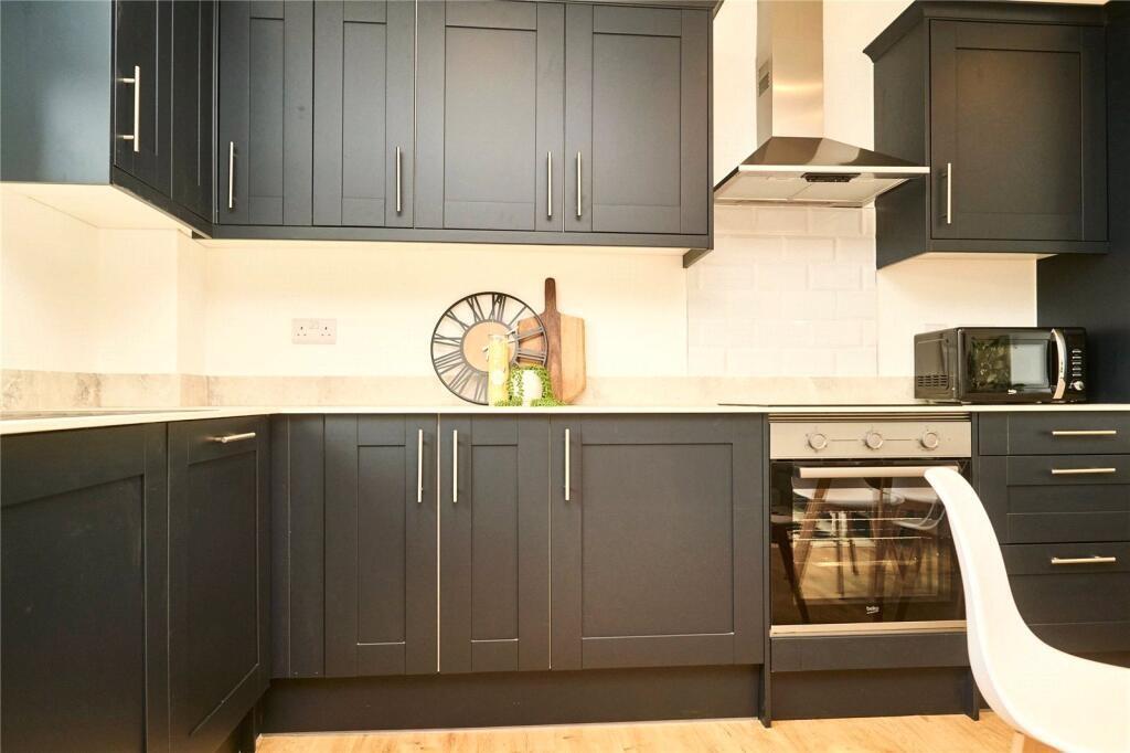 A modern kitchen featuring sleek black cabinetr...