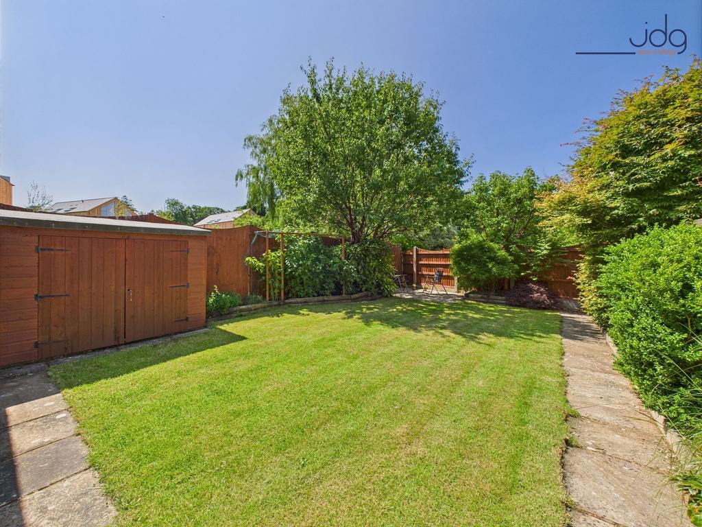 Spacious rear garden with mature plants and...