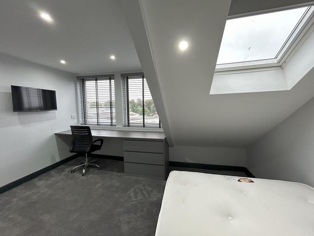 A spacious and modern bedroom featuring a large...