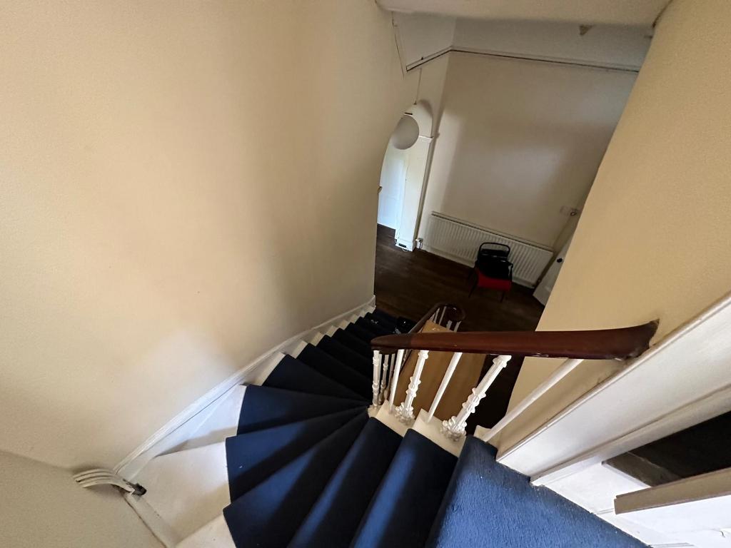 Curved carpeted staircase with white spindles a...