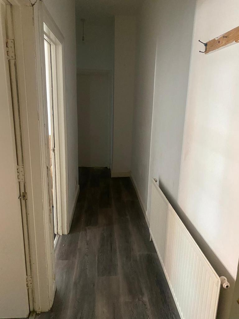 A narrow hallway featuring clean wooden floorin...