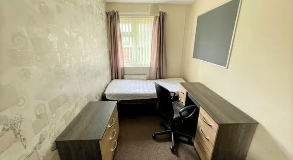 A tidy and well-kept single bedroom featuring a...