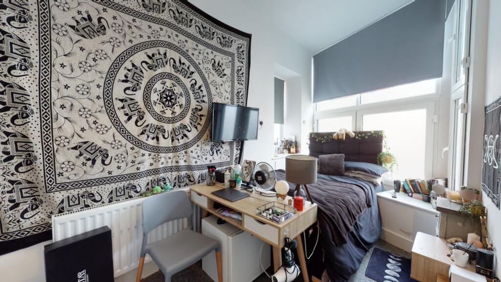 A cozy double bedroom featuring a stylish tapes...