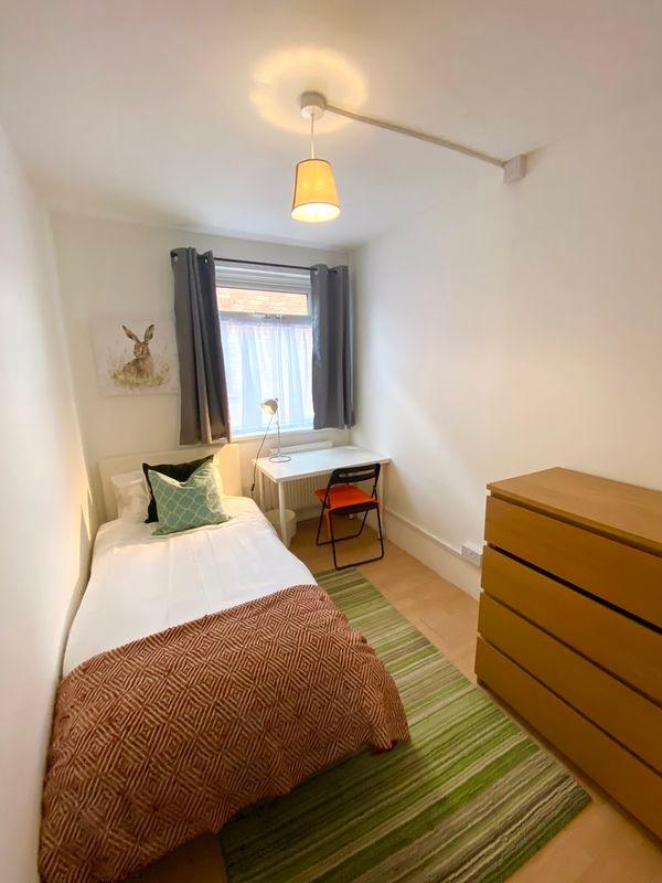 A cozy single bedroom featuring a neatly made b...