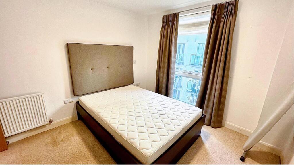Bright double bedroom featuring a large window ...