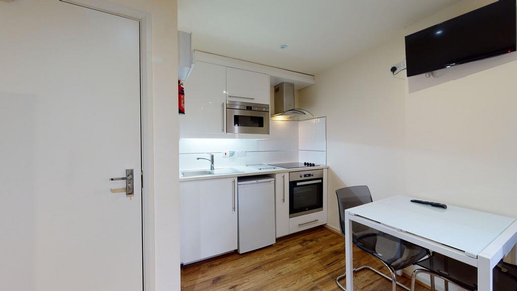 A modern, compact kitchen featuring white cabin...