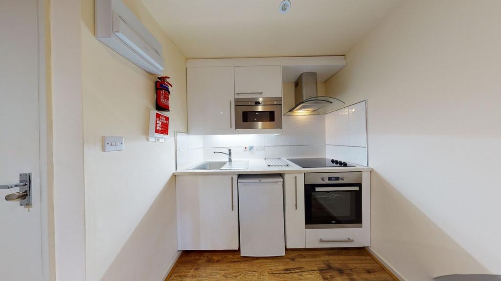 A compact and modern kitchen featuring white ca...